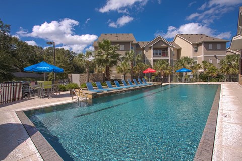 A swimming pool with blue water and a few people around.