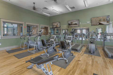 A gym with a variety of exercise equipment including treadmills, stationary bikes, and weight machines.