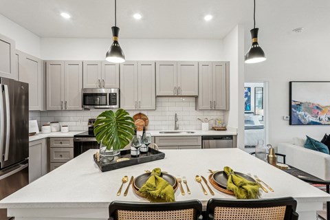 A modern kitchen with a dining table set for two.