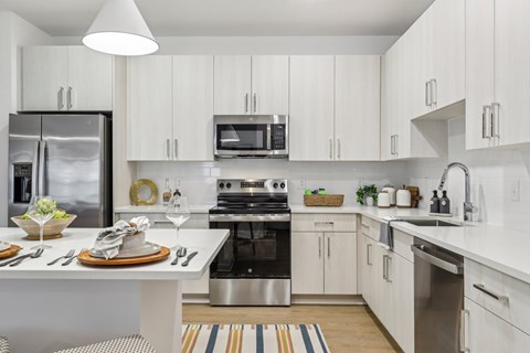 A modern kitchen with white cabinets and stainless steel appliances.
