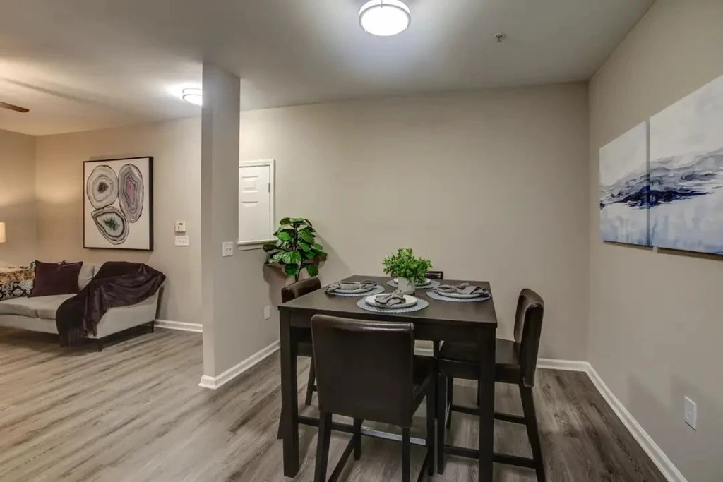 A dining room with a table set for two and a couch with a throw blanket.