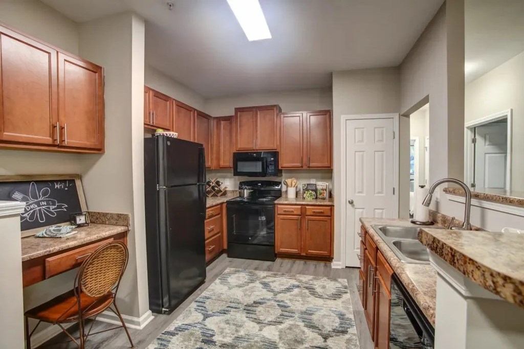 A kitchen with brown cabinets and a black refrigerator.