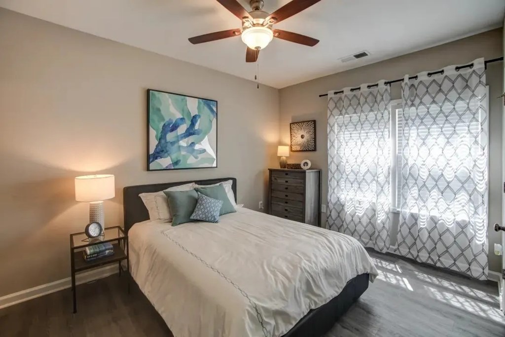 A bedroom with a bed, nightstand, and a painting on the wall.