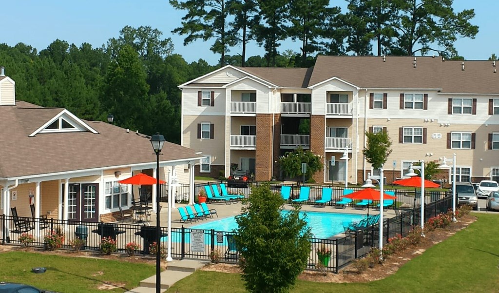 A large apartment complex with a pool and a fence.
