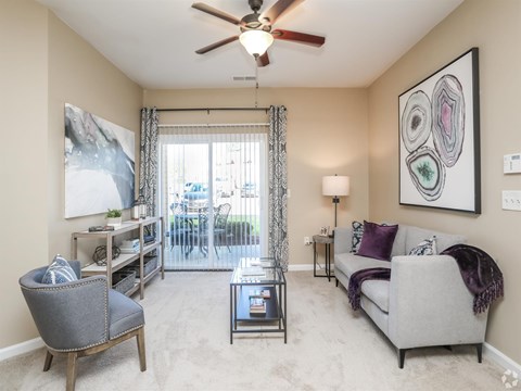 A living room with a grey couch, a chair, a coffee table, and a ceiling fan.