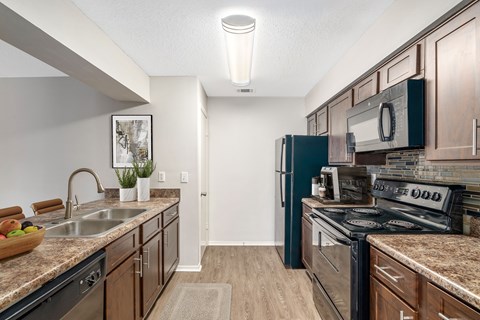 A kitchen with dark wood cabinets and a black refrigerator.