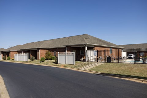 A long building with a grey roof and a fence in front of it.