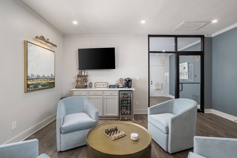 A living room with a television, two chairs, a coffee table, and a painting on the wall.