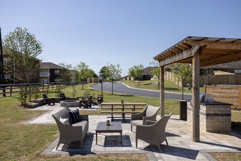 A patio with a table and chairs is surrounded by a grassy area.
