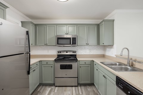 A kitchen with a stove, refrigerator, and microwave.