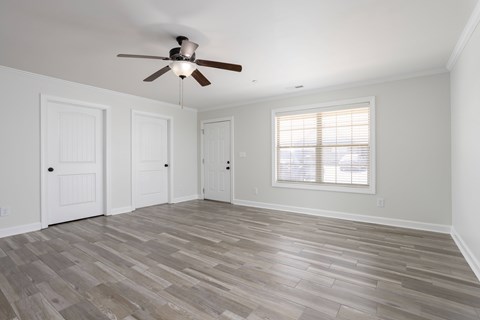 A room with a ceiling fan and wooden flooring.