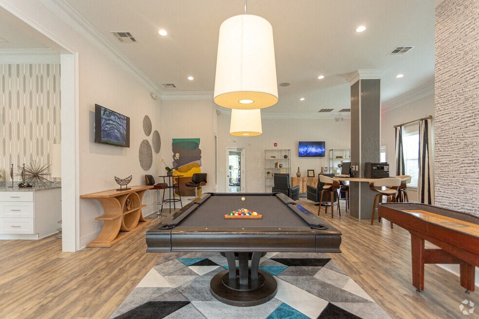 a pool table in a living room with a bar and a television