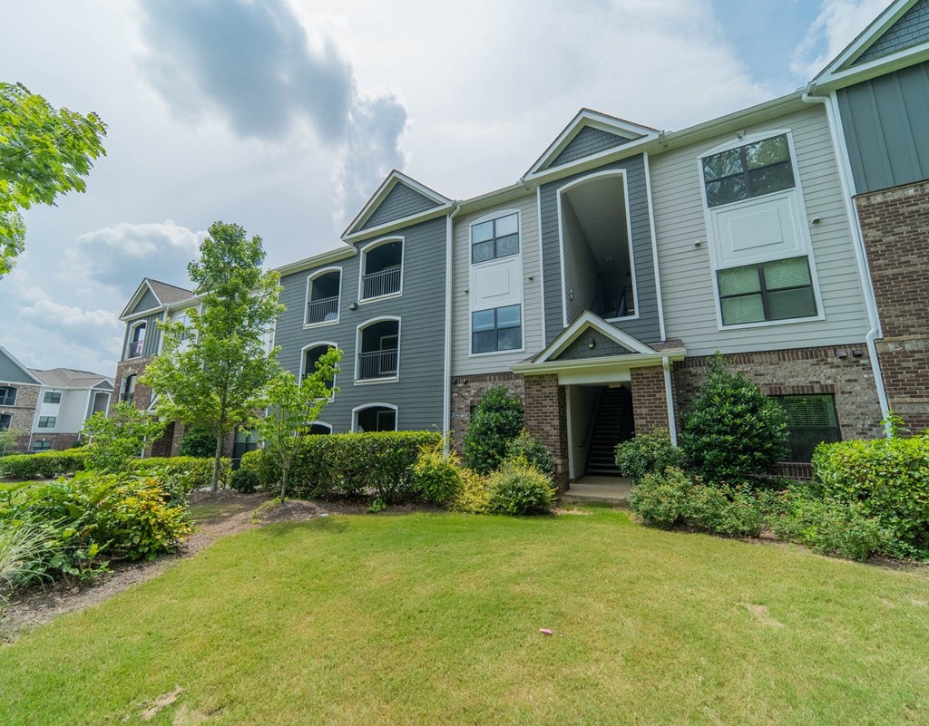 the front yard of an apartment building with grass and bushes