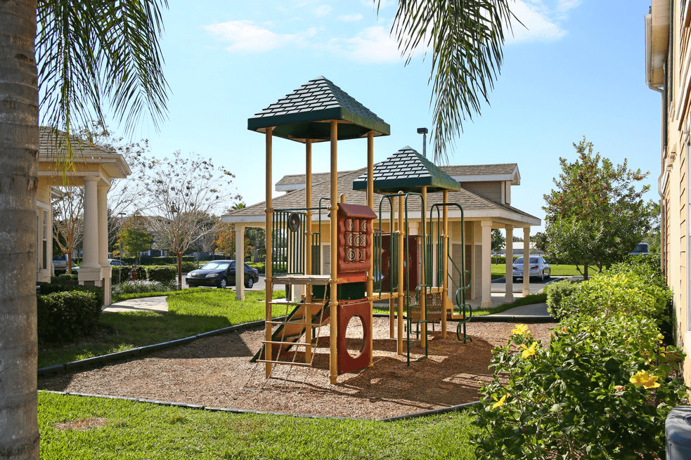 a playground with a swing set in front of a house