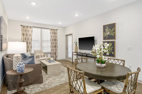 A living room with a brown couch, a coffee table, and a dining table set up.