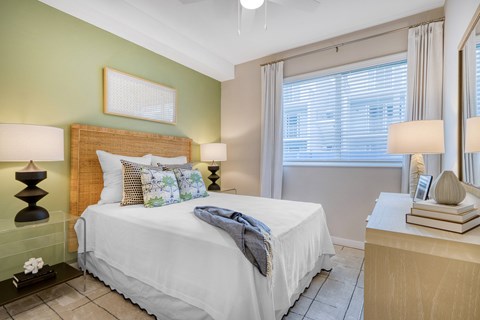 A bedroom with a white bed and a green wall.