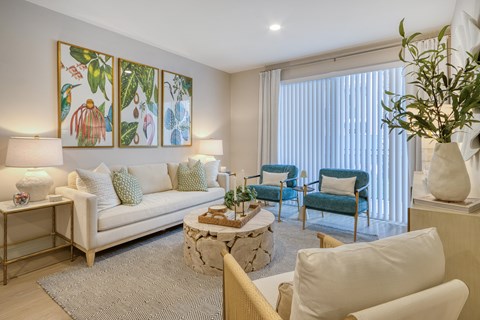 A living room with a white couch, a coffee table, and a painting on the wall.