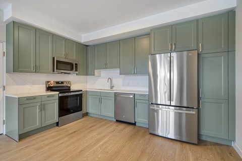 A kitchen with a refrigerator, oven, and microwave.