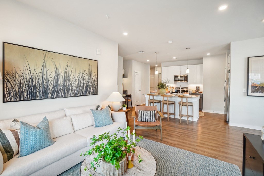a living room with a couch and a table in front of a kitchen