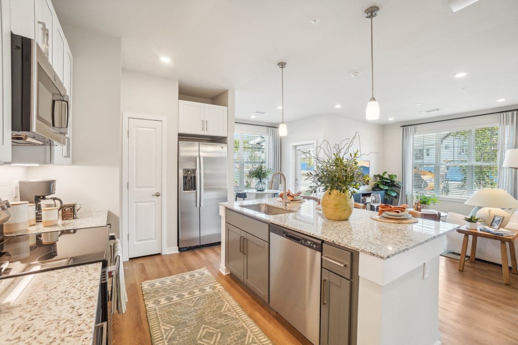 an open kitchen and living room with a large island and stainless steel appliances