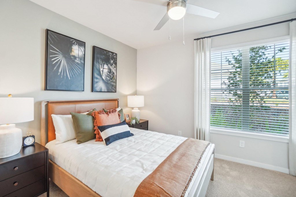 a bedroom with a large window and a ceiling fan