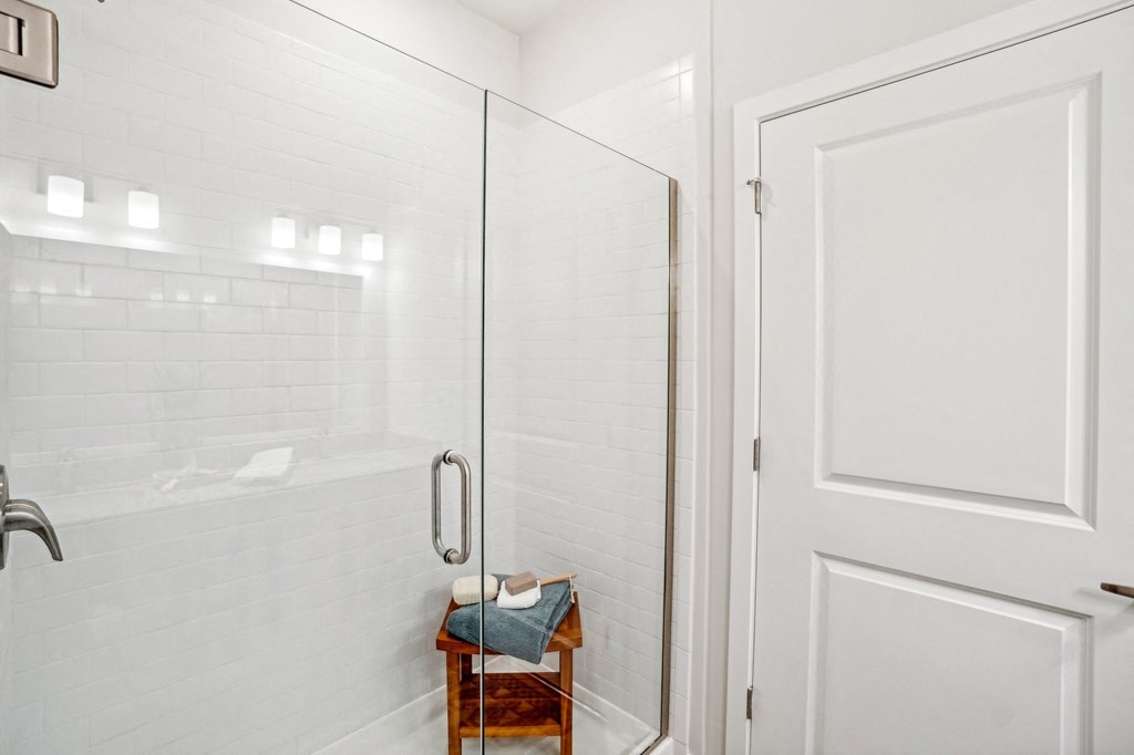 a white tiled bathroom with a glass shower door