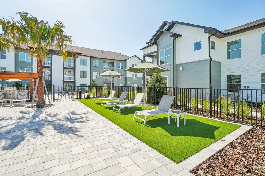a courtyard with lawn chairs and umbrellas in front of apartment buildings