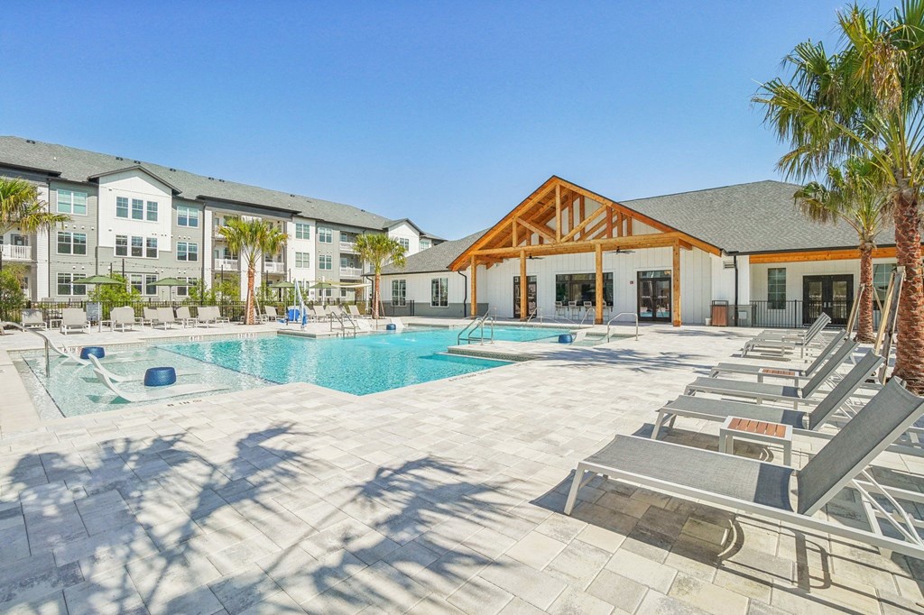 a resort style pool with lounge chairs and a building in the background