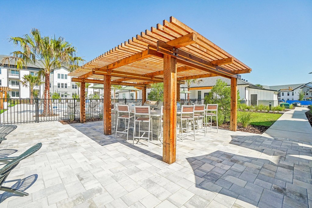 a patio with tables and chairs under a wooden pergola