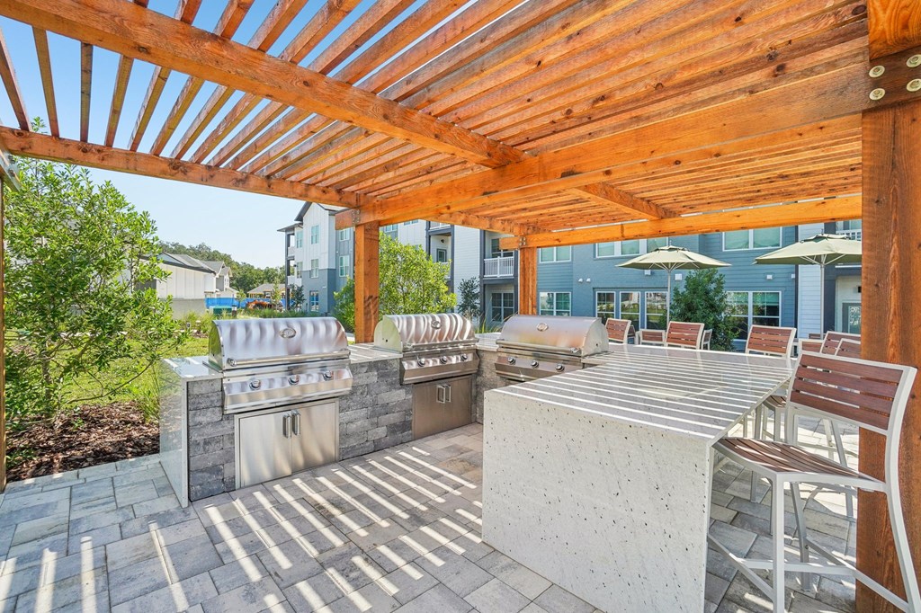 a patio with a grill and a table with chairs