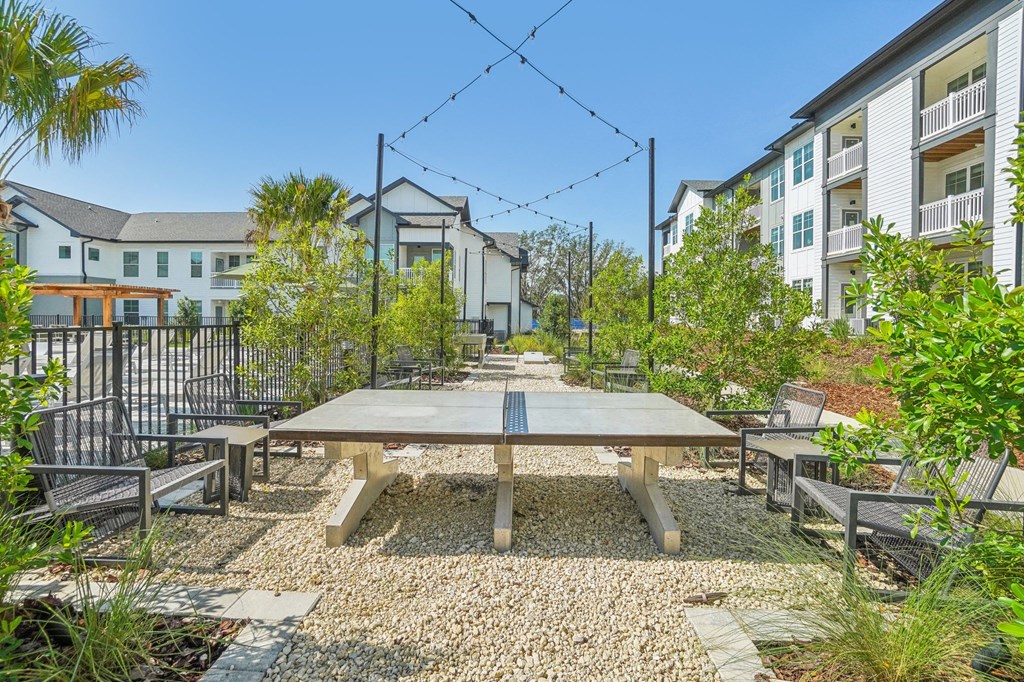 a communal picnic area with a table and benches in front of an apartment building
