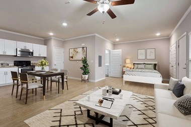 a living and dining room area with a bed in the background and a ceiling fan overhead