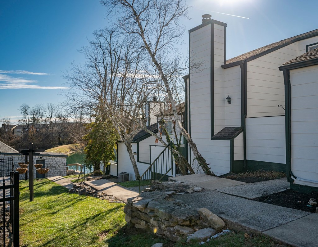 a side view of a house with a sidewalk and a tree