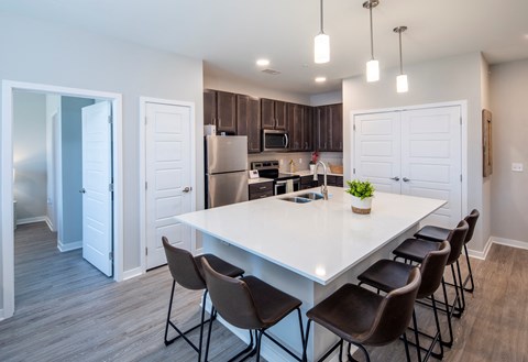 a kitchen with a large white counter top and a stainless steel refrigerator