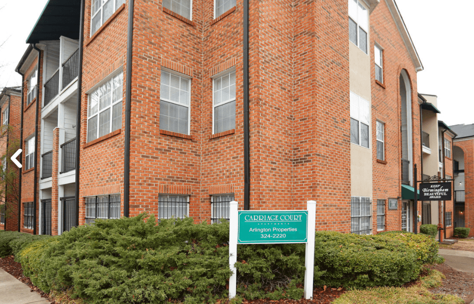 an apartment building with a green sign in front of it