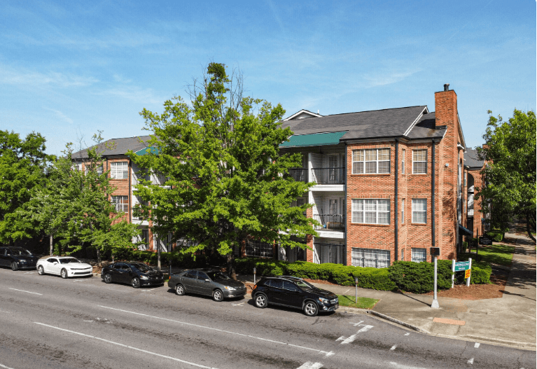 an apartment building on a city street with cars parked in front