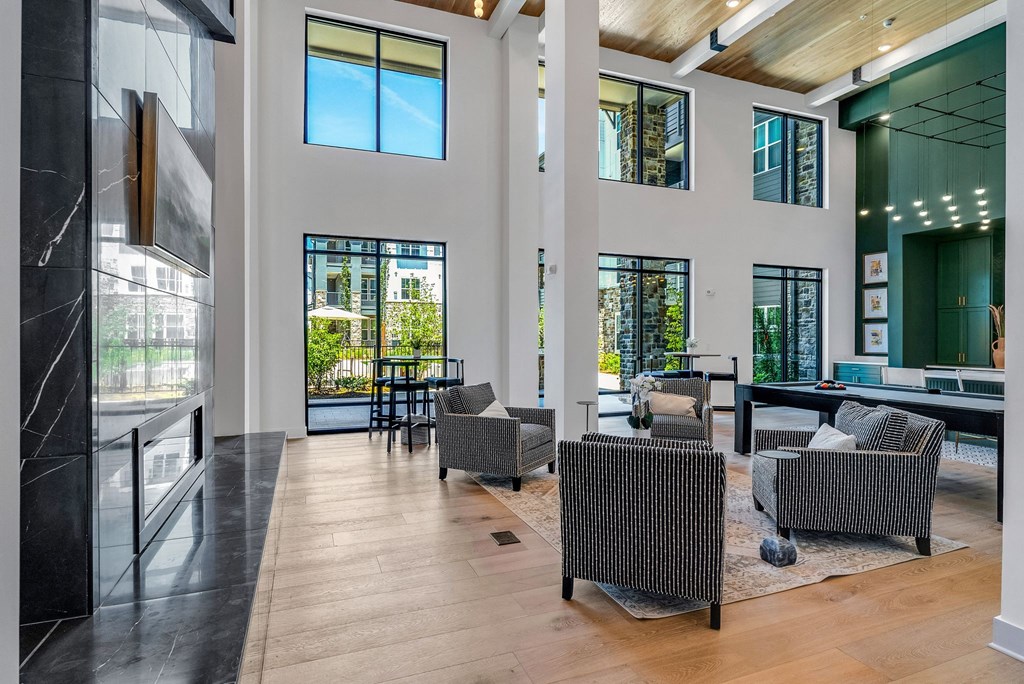 a living room with chairs and a table and windows