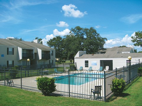 a pool in front of a house with a fence