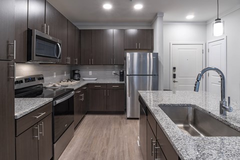 A modern kitchen with dark wood cabinets and stainless steel appliances.