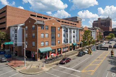 A street view of a city with a red brick building in the foreground.