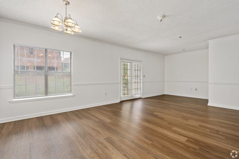 A room with wooden floors and a window with blinds.