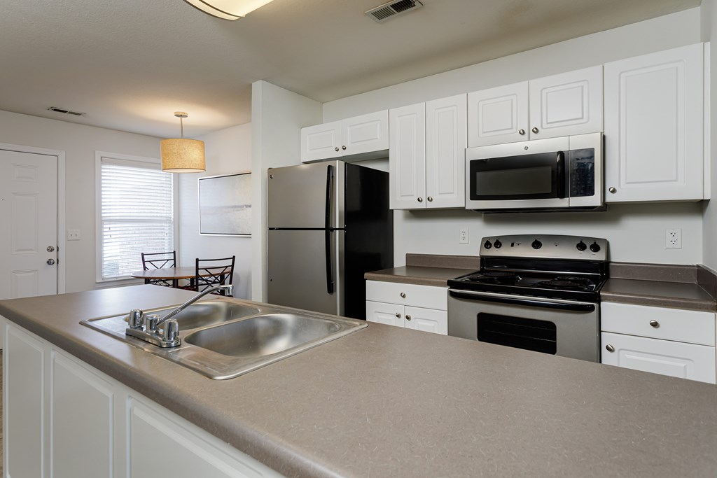 A kitchen with white cabinets and a black refrigerator.