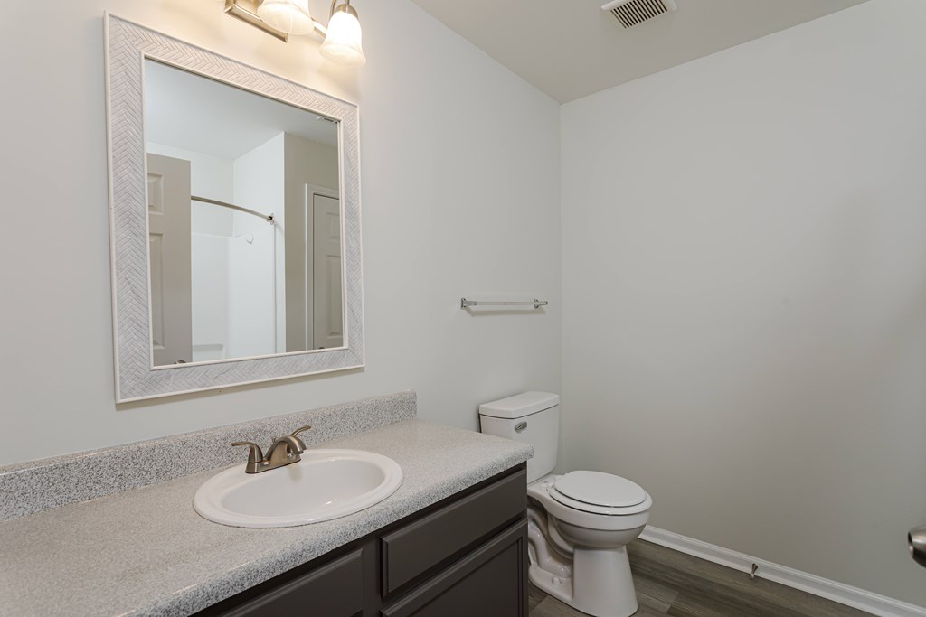 A bathroom with a toilet, sink, and mirror.
