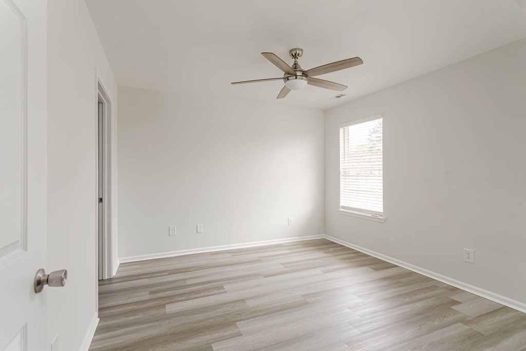 A room with a ceiling fan and wooden flooring.