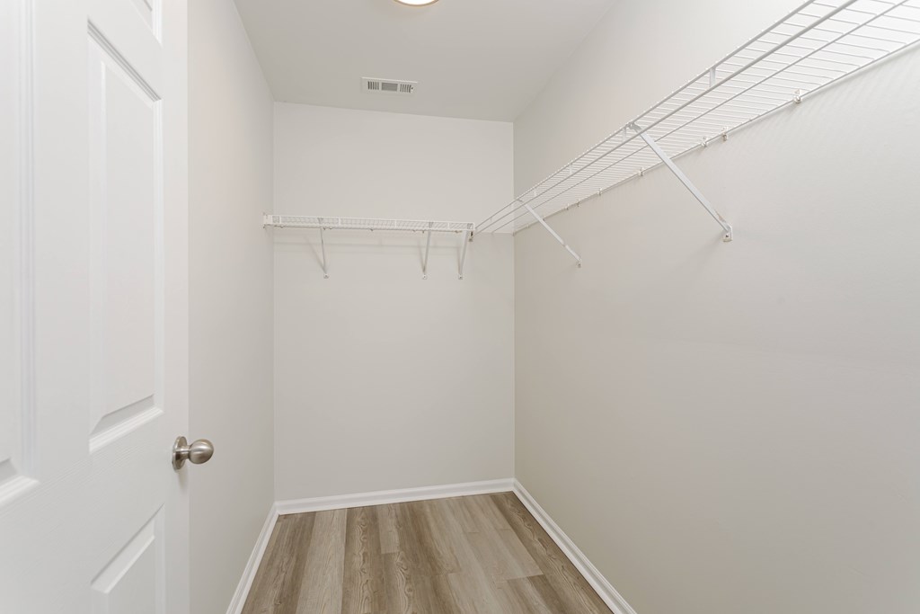 A white closet with a door and a shelf.