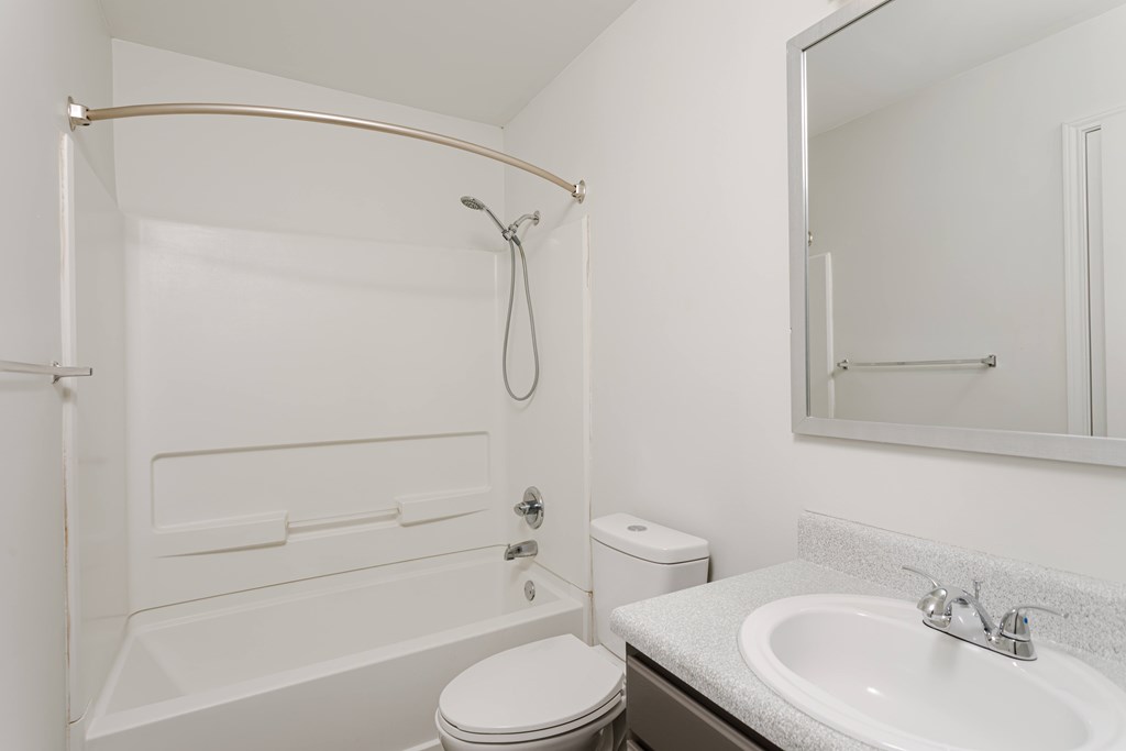 A white bathroom with a toilet, sink, and shower.