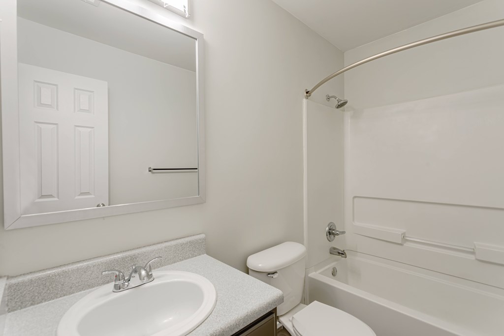 A white bathroom with a sink, toilet, and bathtub.
