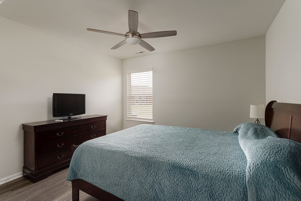 A bedroom with a bed, dresser, and television.