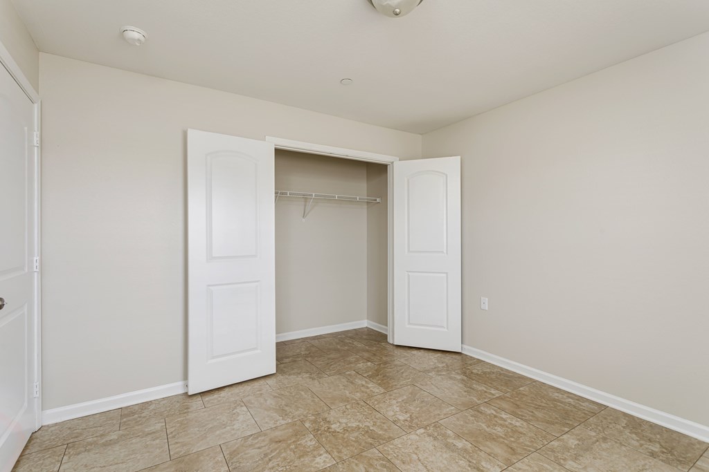 A room with a tiled floor and a closet with a white door.