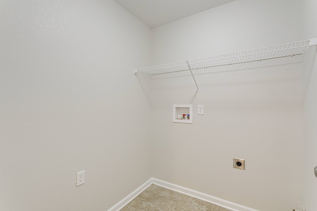 A white wall with a shelf and a picture frame on it.